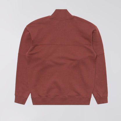A rust-colored long-sleeve sweatshirt shown from the back, featuring a mock neck collar and ribbed cuffs and hem, photographed against a light gray background.