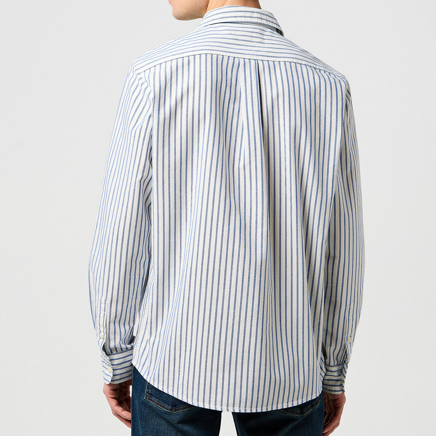 Man wearing a striped shirt from behind on a plain background