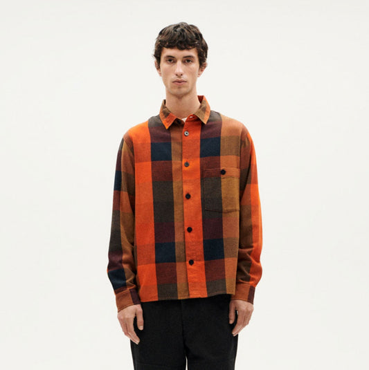 Person wearing a plaid shirt and black pants on a white background