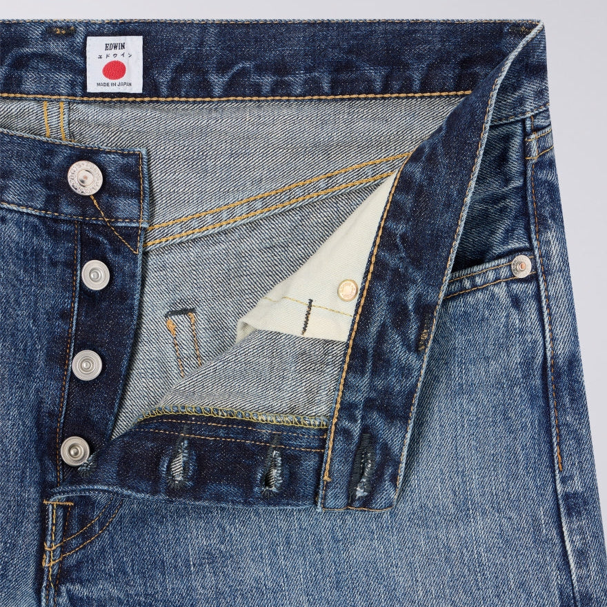 Close-up of blue denim jeans with a brand label on a light gray background