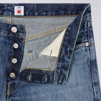 Close-up of blue denim jeans with a brand label on a light gray background