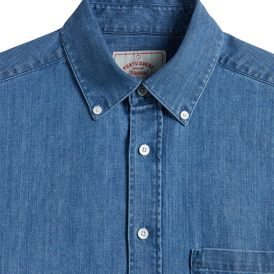 Close-up of a blue denim shirt with a brand label on a white background