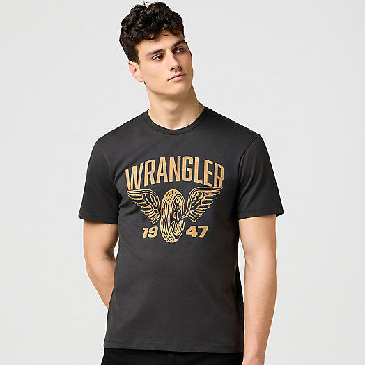 Man wearing a black Wrangler t-shirt with gold logo on a light gray background