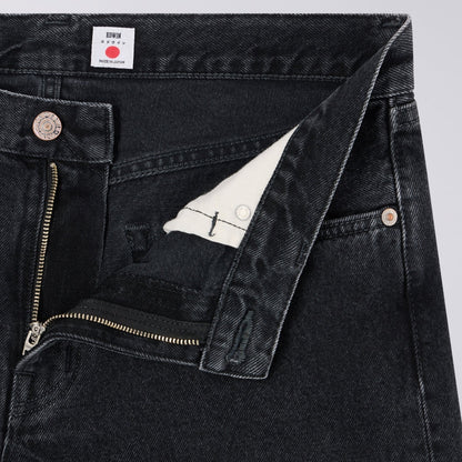Close-up of black denim jeans with a brand label on a light gray background