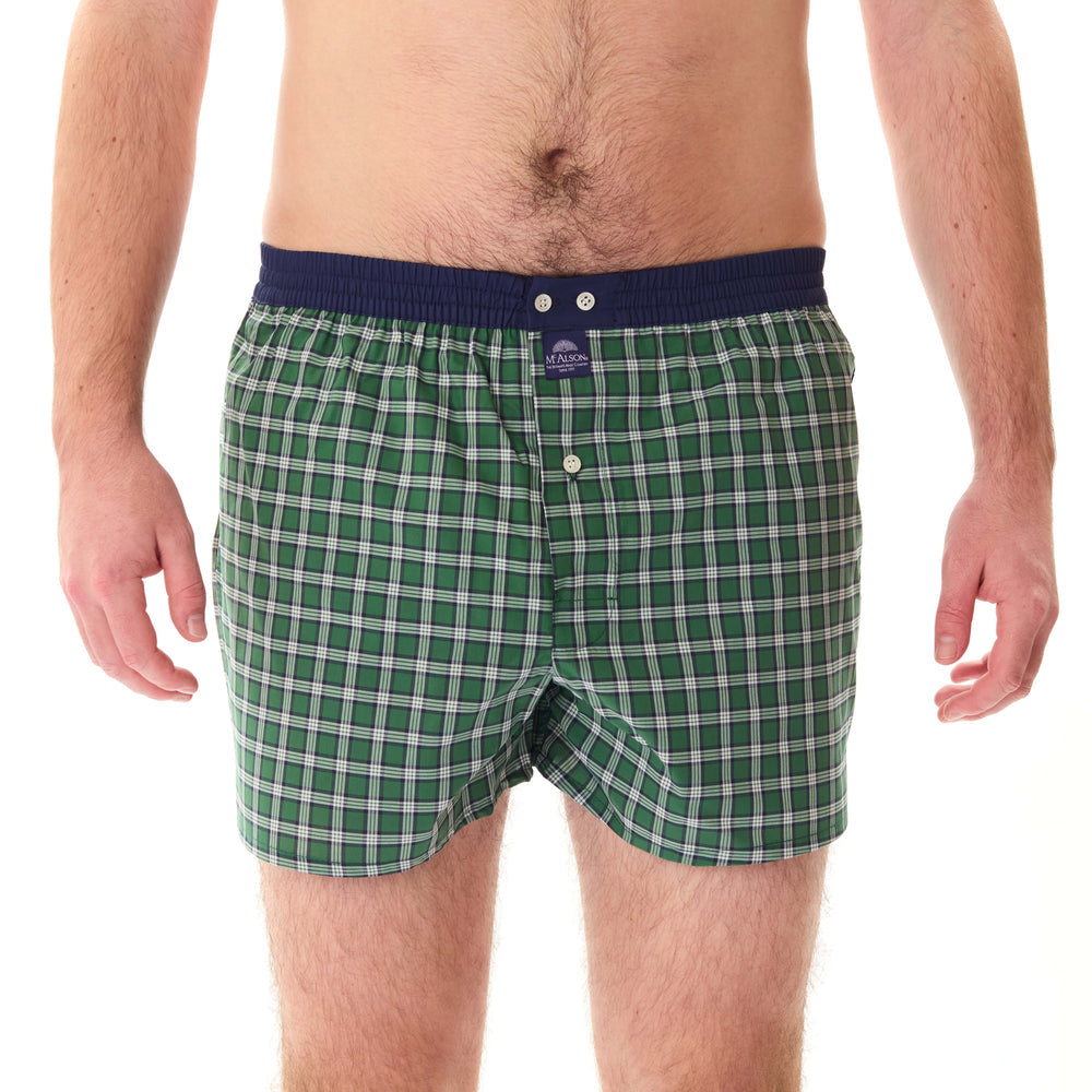 A man wearing green and white plaid boxer briefs with a navy blue elastic waistband, shown from the waist down on a white background.