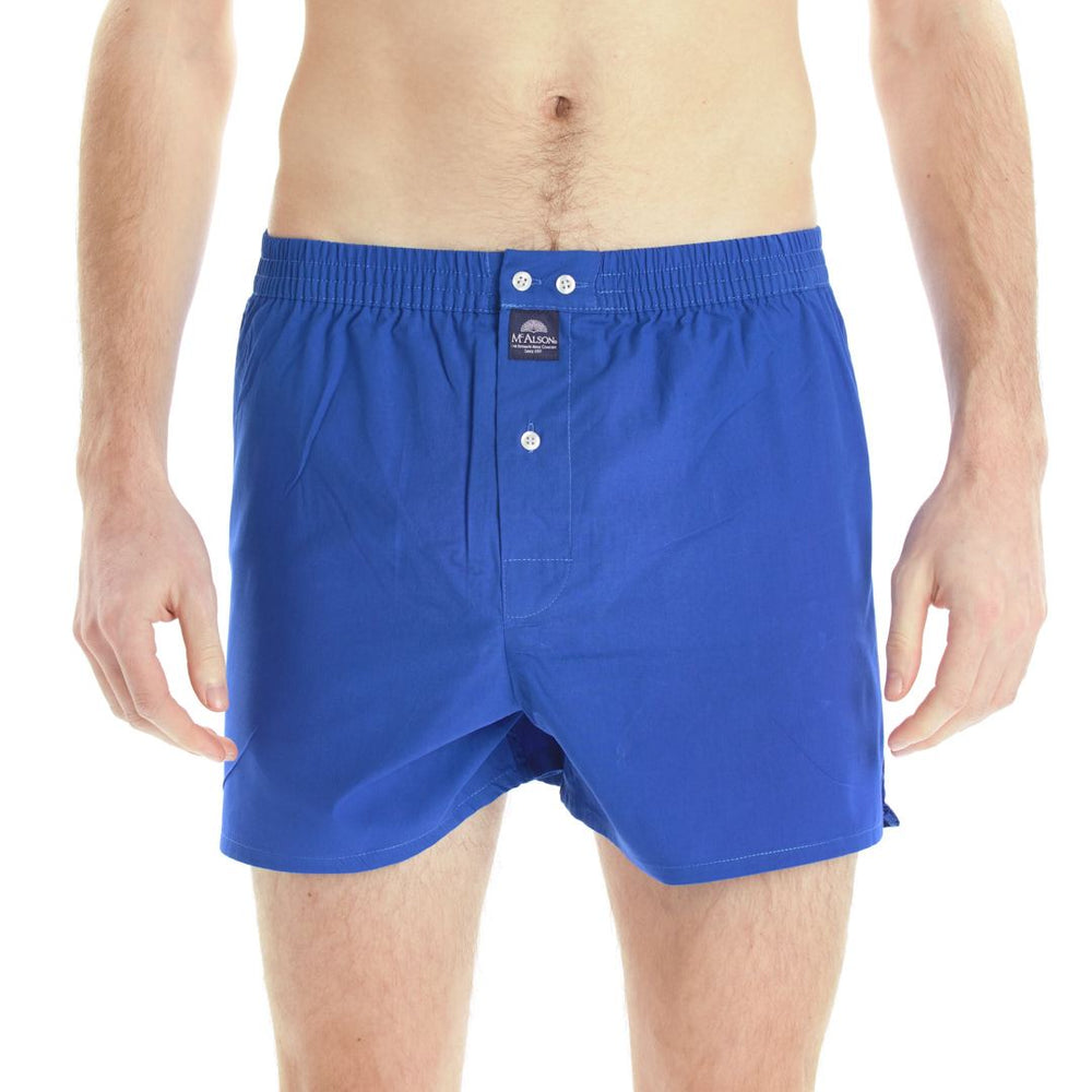 A man wearing royal blue boxer with a buttoned front and elastic waistband, shown from the waist to mid-thigh against a plain white background.