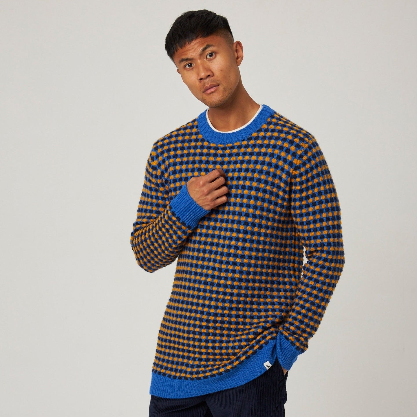 Man wearing a checkered sweater with blue accents on a plain background