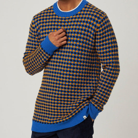 Man wearing a checkered sweater with blue accents on a plain background