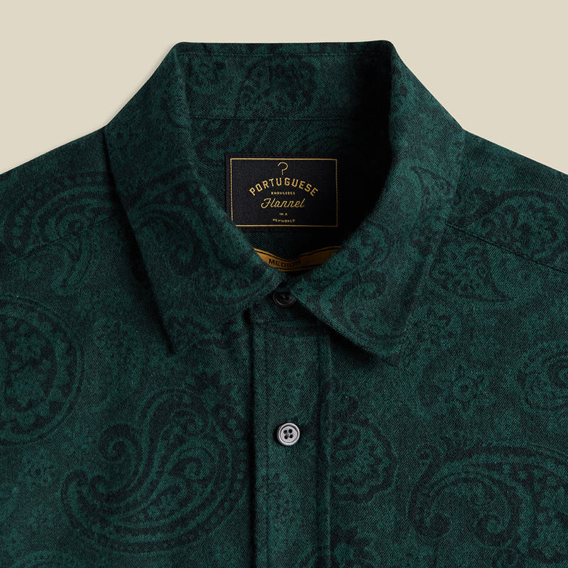 Dark green patterned shirt with a brand label on a beige background