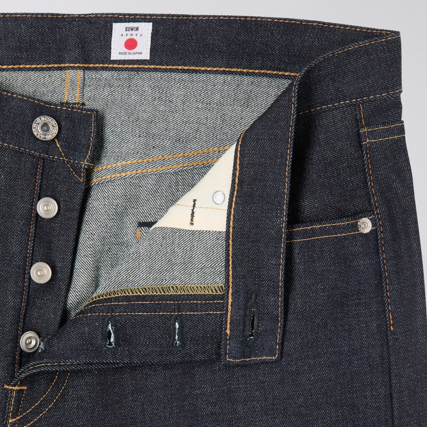 Close-up of dark blue denim fabric with a brand label on a gray background