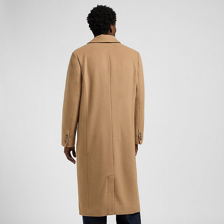 Person wearing a beige overcoat on a light gray background