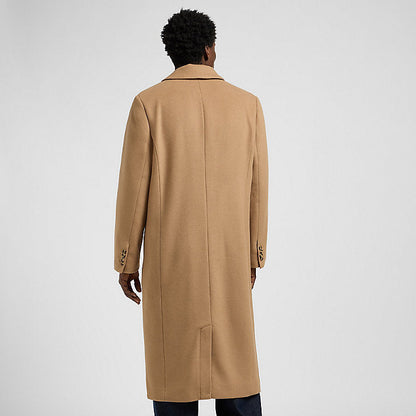 Person wearing a beige overcoat on a light gray background