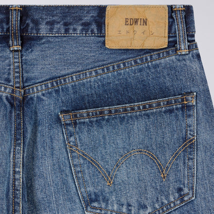 Close-up of blue jeans with a visible Edwin label on a light gray background