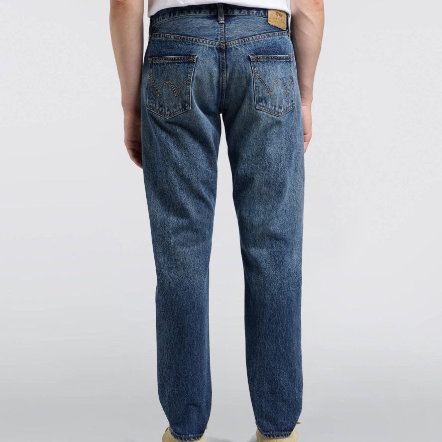 Person wearing blue jeans on a plain background