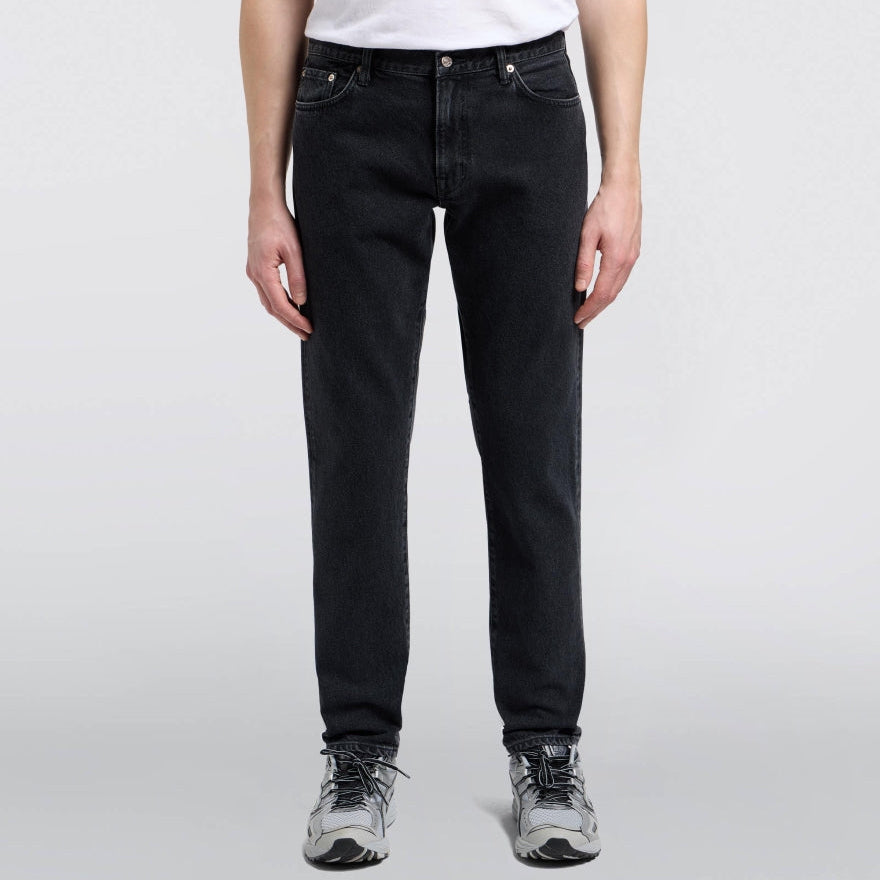 Person wearing black jeans and a white shirt on a light gray background