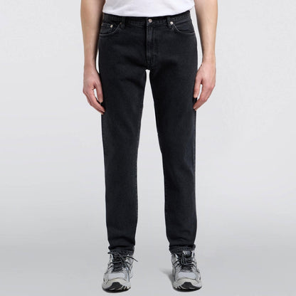 Person wearing black jeans and a white shirt on a light gray background