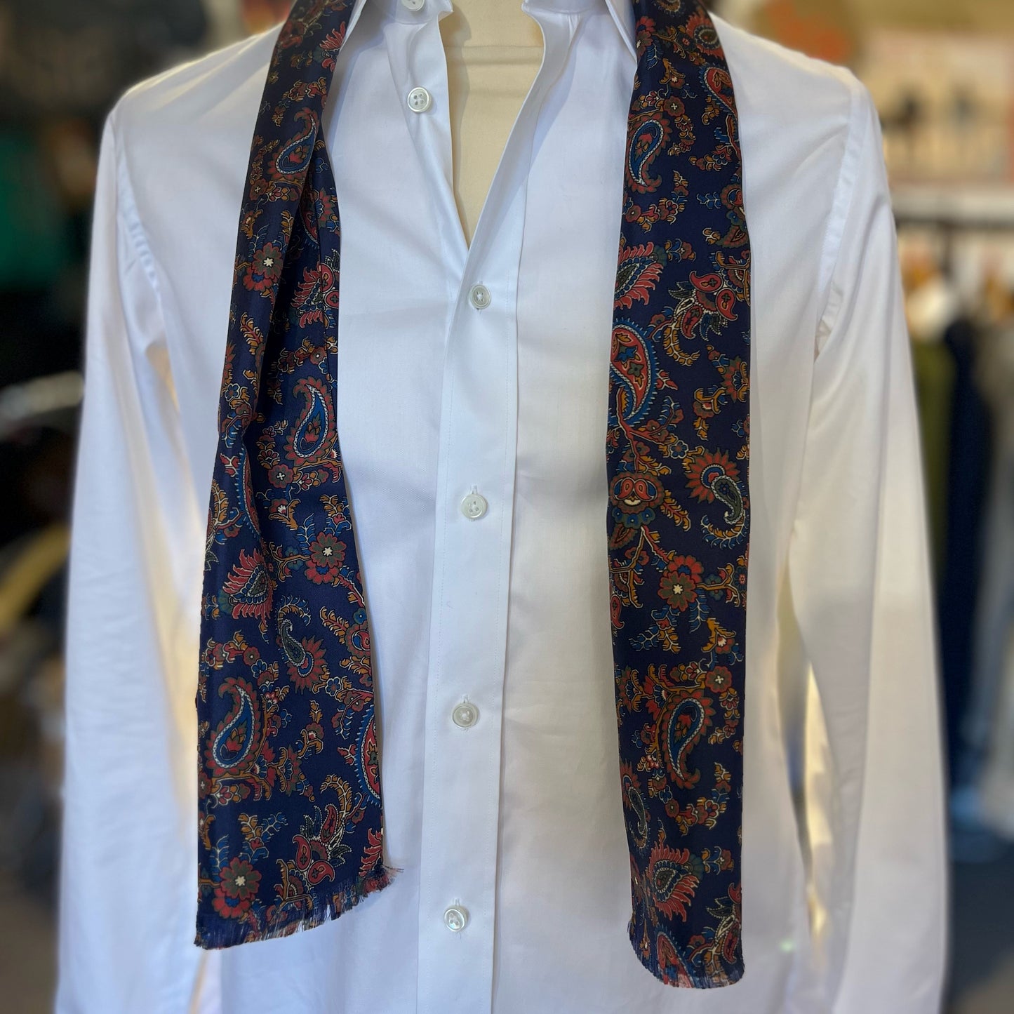 A blue tootal scarf with paisley pattern draped around the shoulders of the mannequin.