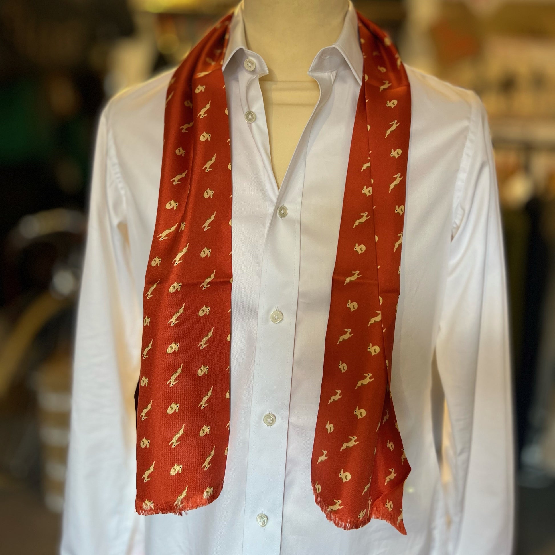 An orange tootal scarf with a printed pattern of bunny rabbits draped around the neck of a mannequin