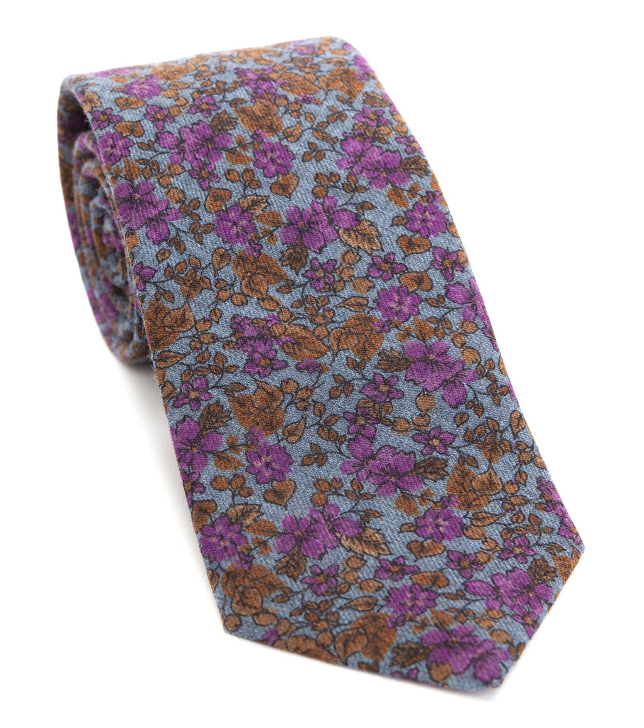 Luxury woven wool tie designed and made exclusively for Regent featuring a soft sky blue overgrown with autumnal gold-brown leaves spurting purple flowers.