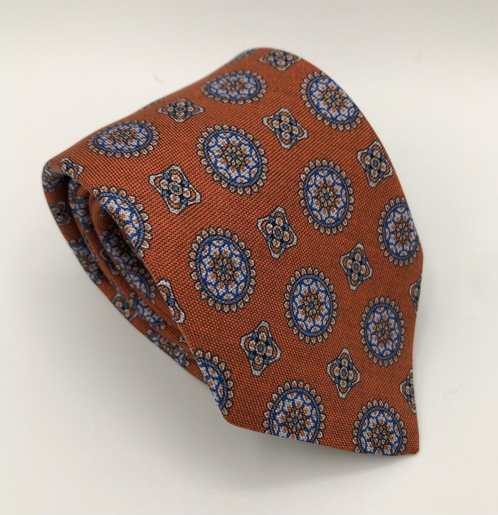 A luxury wool and silk tie designed by and handmade exclusively for Regent. A beautiful, smart burnt orange / rust red is picked out by church-like stain-glass geometric shapes.